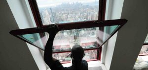 man looking out window into a city