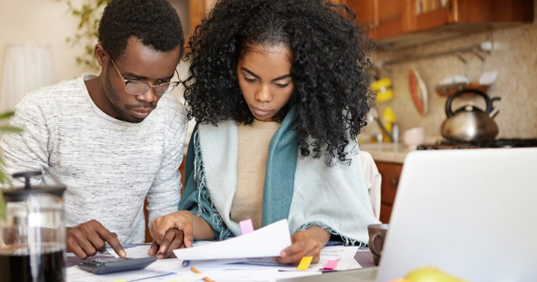 couple looking at a piece of paper while calculating the cost of something