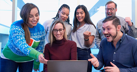 Group of people looking at laptop cheering